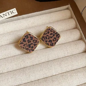 Elegant leopard print rhombus stud earrings with gold-toned frame displayed in jewelry box