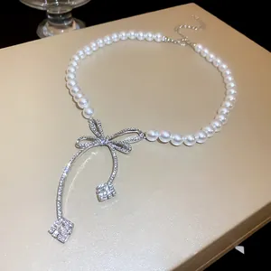 Macro detail of a luxurious pearl necklace with a sparkling rhinestone-encrusted bow.