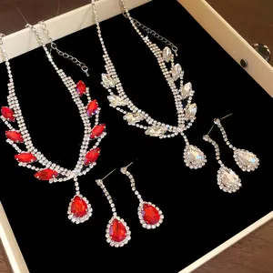 Détail des parures collier et boucles d'oreilles en strass rouge et argent en boîte.
