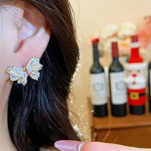 Close-up of delicate butterfly stud earring with sparkling zircons on model's ear