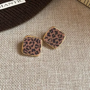 Macro view of stylish leopard print diamond-shaped stud earrings with gold-toned edges