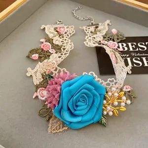 Detail shot of a handmade lace choker with a vibrant blue fabric rose and pearls