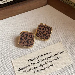 Detailed macro view of elegant leopard print square stud earrings with gold plating.
