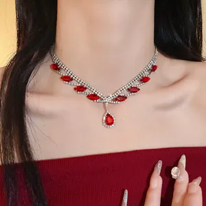 Élégant collier argenté orné de strass rouges éclatants et d'un pendentif en goutte.