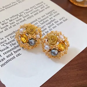 Vintage court style gold floral earrings with pearls and crystals on book page