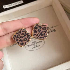 Close-up of square leopard print stud earrings with elegant gold borders.