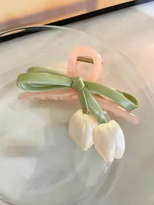 Detailansicht der Stoff-Tulpenanhänger und des grünen Bandes an einer rosa Haarklammer.