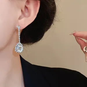 Boucles d'oreilles pendantes en zircone en forme de poire portées par un modèle élégant