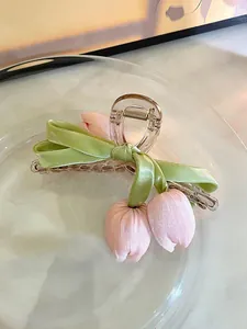 Detail einer eleganten Haarklammer aus Acryl mit rosa Stofftulpen und grünem Band.