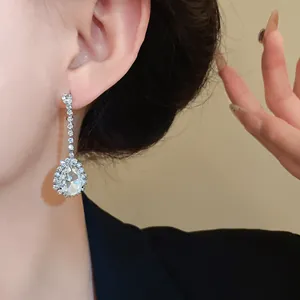 Détail d'une élégante boucle d'oreille pendante argentée avec un cristal en forme de poire
