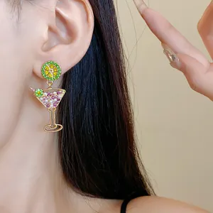 Close-up detail of cocktail glass earrings with lime slice and colorful rhinestones.