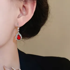 Gros plan d'une élégante boucle d'oreille goutte rouge avec halo de diamants