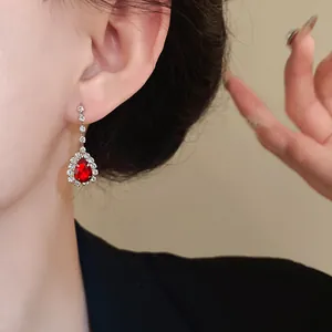 Gros plan élégant d'une boucle d'oreille goutte rouge avec strass étincelants