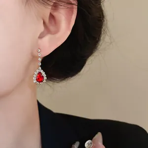 Gros plan de boucles d'oreilles goutte rouges élégantes avec halo de cristal brillant