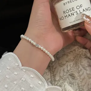 Bracelet en perles élégant avec accent en zircone porté au poignet avec dentelle.