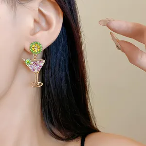 Close-up detail of a gold-plated cocktail glass earring with lime and pink rhinestones.