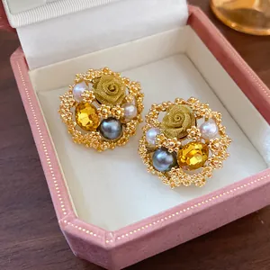 Macro view of vintage gold rose earrings with yellow gems and pearls in pink box