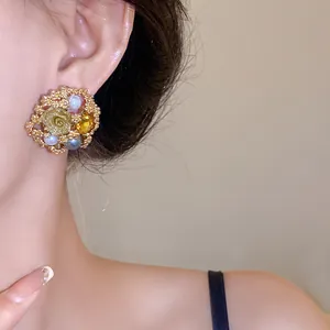 Close-up of vintage floral gold earring with pearls and yellow rhinestones on a model's ear