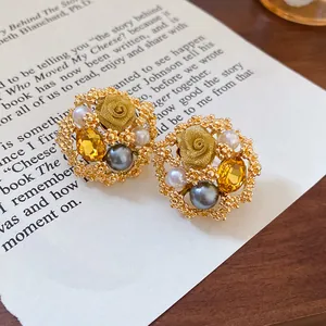 Detailed macro view of vintage gold flower stud earrings with pearls and amber stones