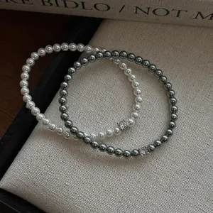 Détail de haute qualité des bracelets en perles blanches et grises avec charms zircon