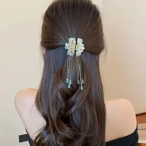 Back view of elegant butterfly tassel hair claw clip on long wavy brown hair