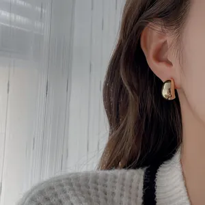 Détail en gros plan d'une boucle d'oreille en forme de C dorée et brillante
