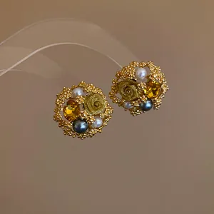 Macro view of vintage golden flower stud earrings with elegant pearls and yellow crystal