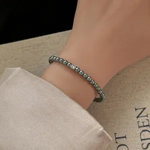 Gros plan d'un bracelet en perles gris foncé orné d'un zircon carré brillant