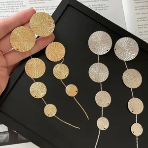 Macro view of textured metal round disc tassel drop earrings in both gold and silver tones