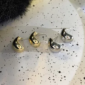 Gros plan de boucles d'oreilles minimalistes en forme de C, finitions or et argent
