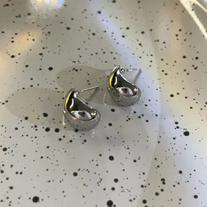 Vue rapprochée de boucles d'oreilles clous en métal en forme de C, fini argent brillant