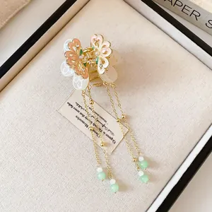 Close-up detail of an elegant butterfly hair claw clip with long beaded tassels.