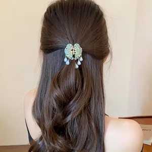 Detailed view of elegant butterfly hair claw clip with pearl tassels on long hair