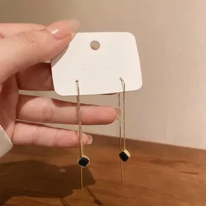 Orecchini lunghi a nappa dorati eleganti con raffinati pendenti geometrici neri.
