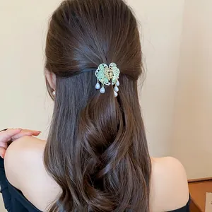 Detailed view of an elegant butterfly hair claw with pearl tassels on a model's updo.