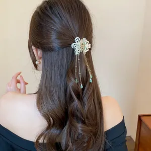 Elegant butterfly tassel hair claw clip detailed view on a model with long brown hair.