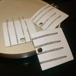 Primo piano di eleganti fermagli per capelli argentati con strass su cartoncini bianchi