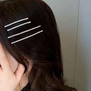 Dettaglio di quattro eleganti forcine minimaliste con strass argentati indossate sui capelli