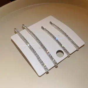 Dettaglio macro di eleganti fermagli per capelli con strass luccicanti su cartoncino.
