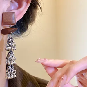 Detailansicht von Vintage-Holzohrringen im Ethno-Stil mit dreistufigen Silberglocken