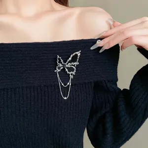Eleganter schwarzer Schmetterling-Brosche mit silbernen Quasten auf einem Strickpullover.