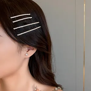 Dettaglio di fermagli per capelli con strass acconciati su capelli scuri mossi.