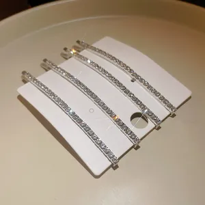 Vista dettagliata di quattro eleganti fermagli per capelli con strass argento su cartoncino.