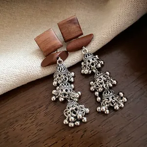 Detailaufnahme ethnischer Retro-Holzohrringe mit dreifachen silbernen Jhumka-Quasten