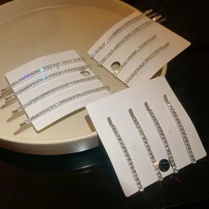 Dettaglio di forcine argentate con strass scintillanti su cartoncini di presentazione.