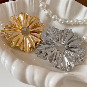 Detailed view of the metallic flower earrings with pleated texture in gold and silver finish