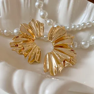 Detailed macro view of gold-toned pleated fan-shaped metallic flower earrings.
