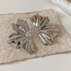 Macro view of silver metallic flower earrings with intricate pleated fan texture