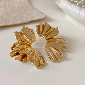 Macro view of gold pleated fan-shaped flower earrings with elegant metallic texture