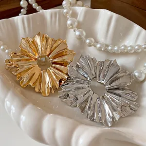 Detailed macro view of metal flower fan pleated earrings in gold and silver colors